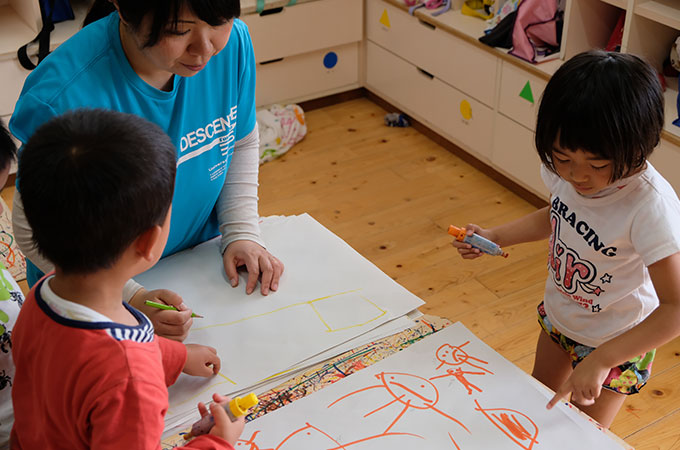 子どもに絵を書いてあげている先生の写真